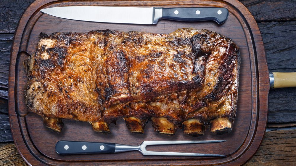 Full rack of smoked ribs on a carving board